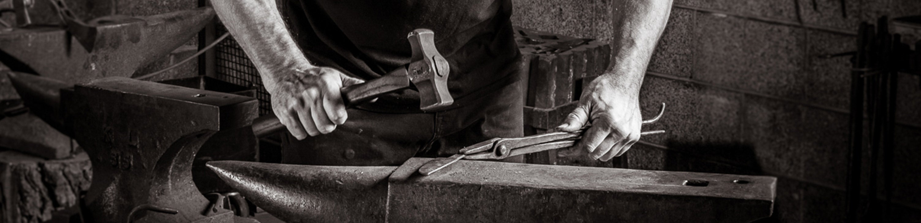 hand with hammer hitting knife into shape